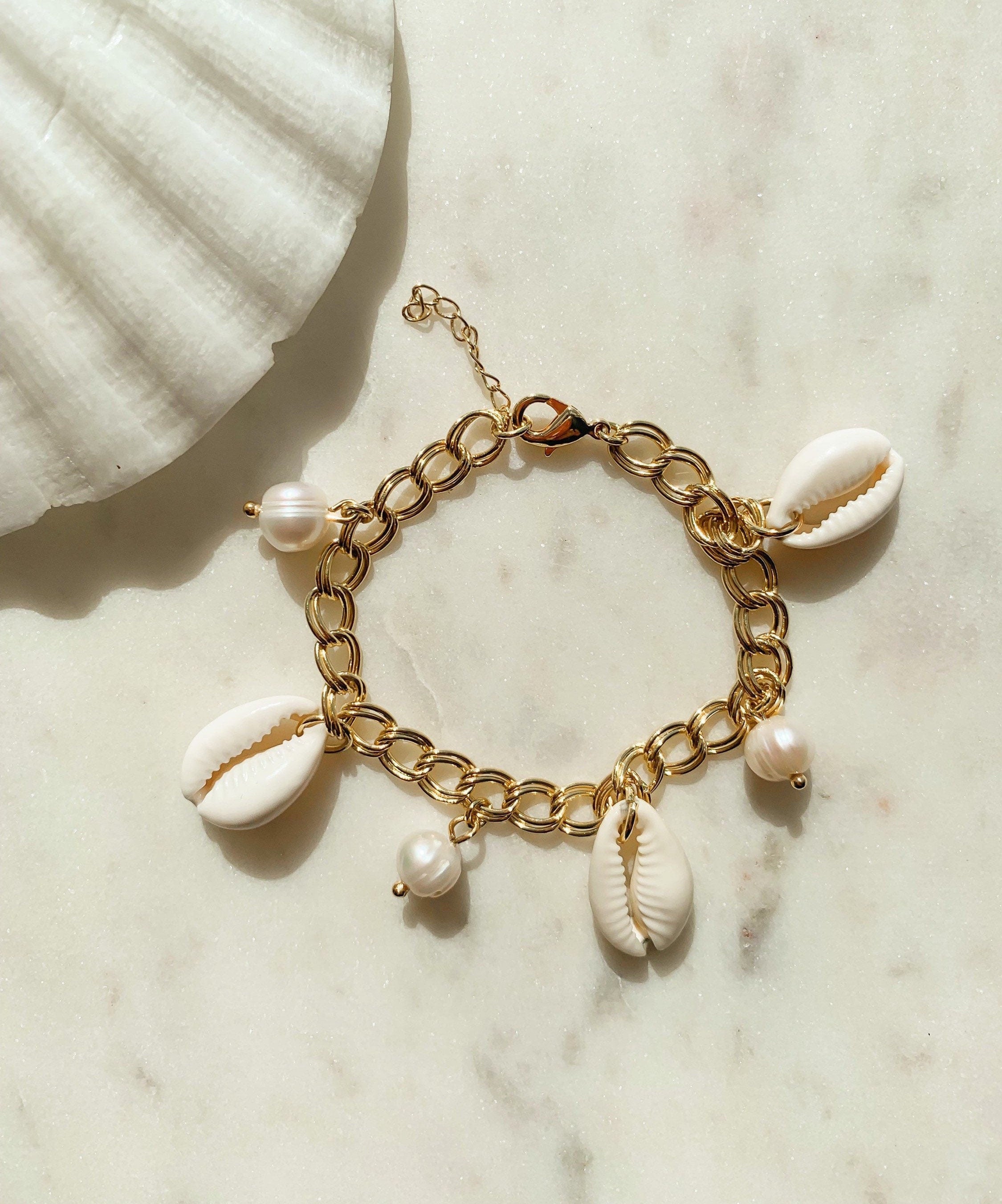 Pulsera dorada ajustable con conchas naturales y dijes de perlas de agua dulce, joyería bohemia hecha a mano.
